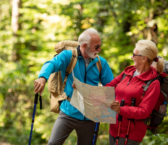 Senior couple of tourists looking at map in forest